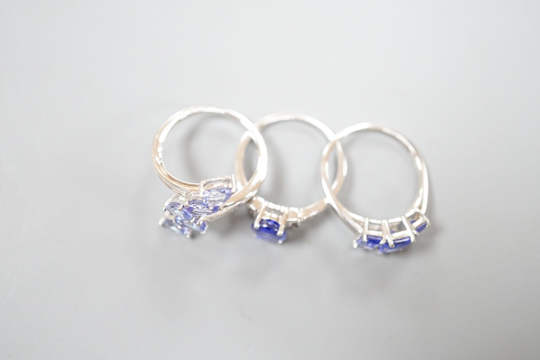 Three assorted modern 9ct white gold and tanzanite set dress rings, gross weight 8.6 grams.